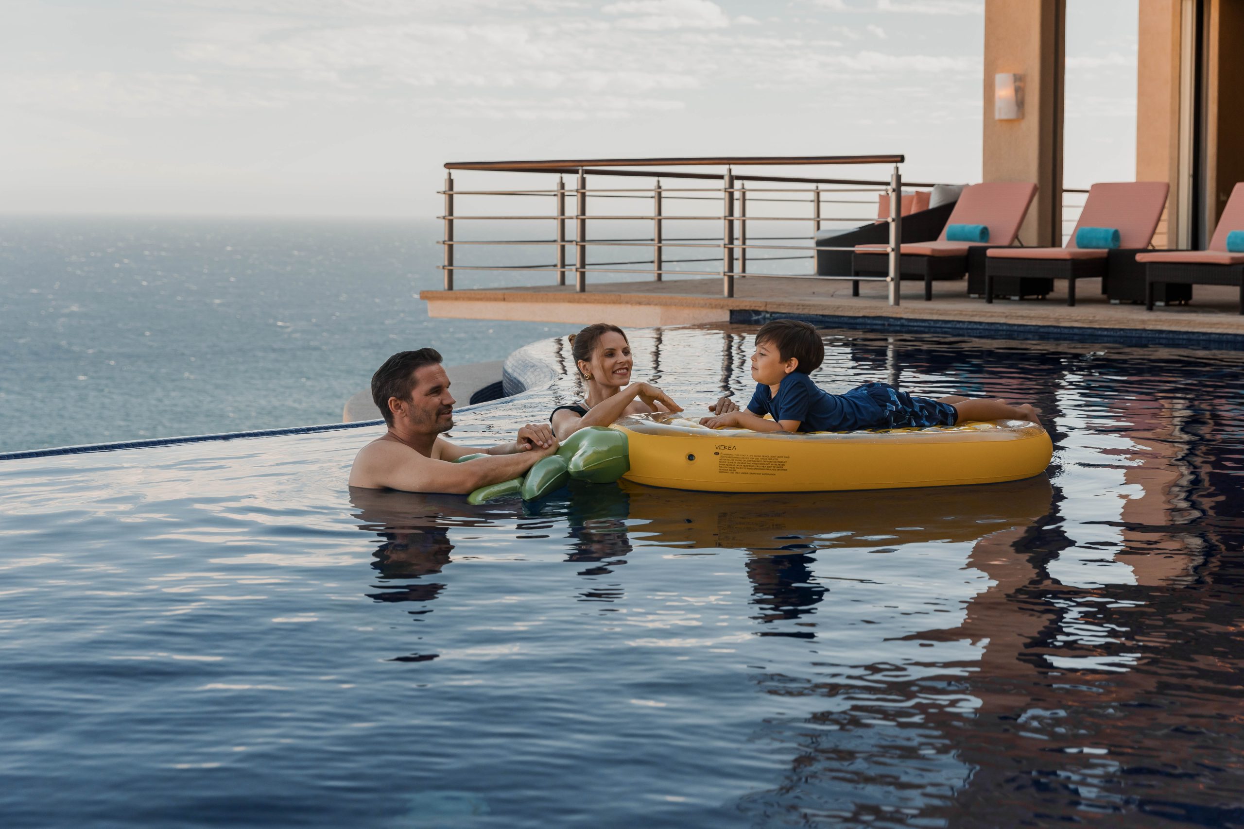 family in pool overlooking the ocean